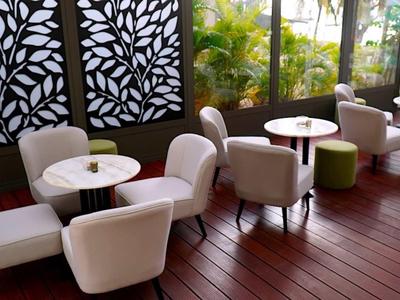 Pohodlná posezení s bílými křesly a kulatými stolky na terase s dřevěnou podlahou.