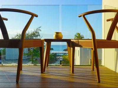 Dva dřevěné židle a stůl s výhledem na moře na terase při západu slunce.