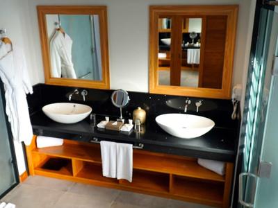 Moderní koupelna s dvojitými umyvadly, zrcadly a bílými ručníky.