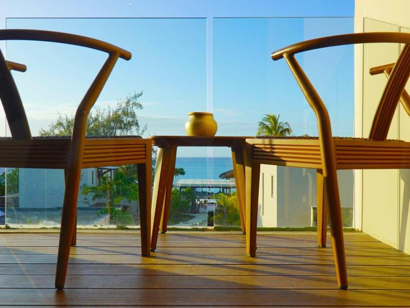 Dva dřevěné židle a stůl s výhledem na moře na terase při západu slunce.