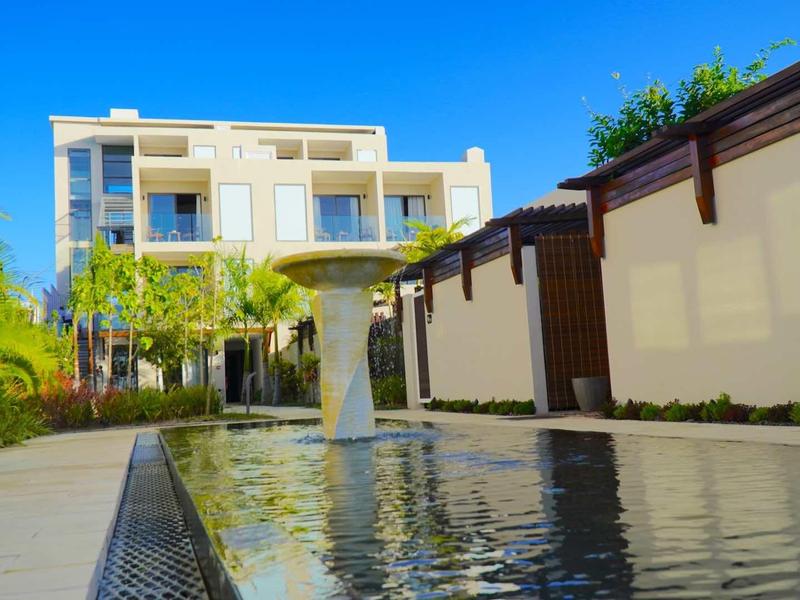 Moderní obytný komplex s bazénem a modrou oblohou v pozadí.