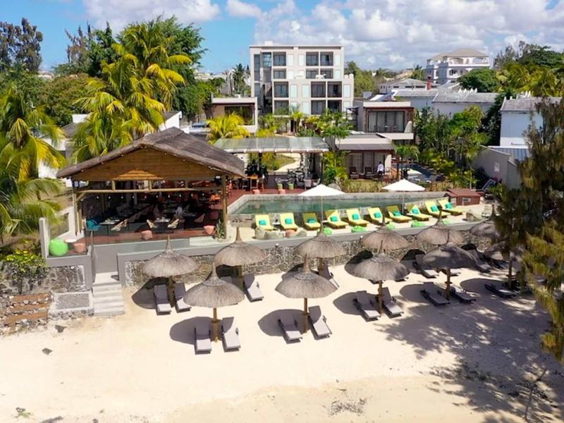 Plážové letovisko s lehátky, slunečníky a tropickými rostlinami u moře