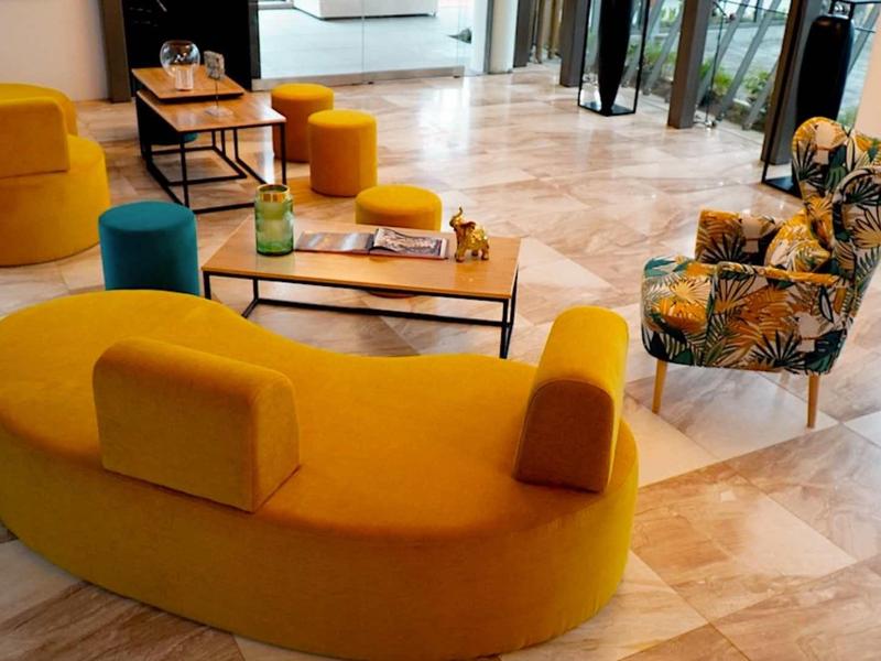 Moderně zařízená hotelová lounge s žlutým sezením a velkými okny.