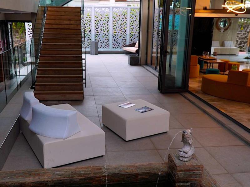 Moderní hotelová hala s posezením, schody a skleněnými dveřmi.