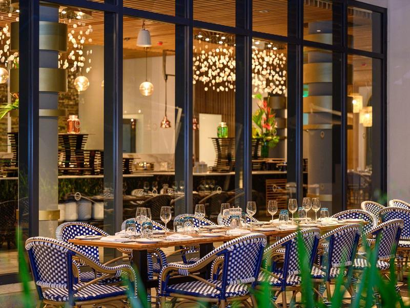 Elegantní restaurace s prostřenými stoly a modrými židlemi, osvětlená útulnými lampami.