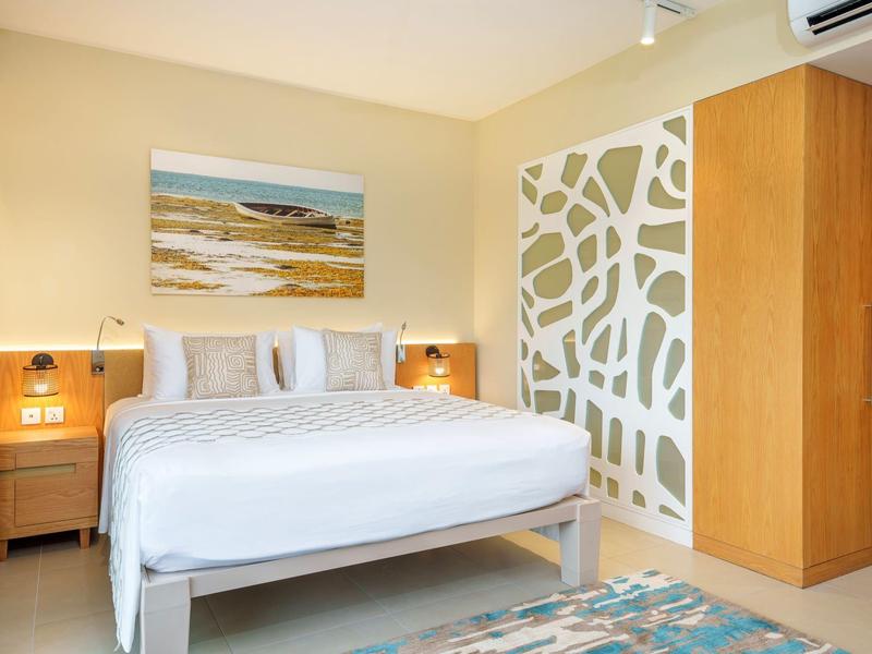 Světelná ložnice s velkou postelí, nočními stolky a moderní skříní.