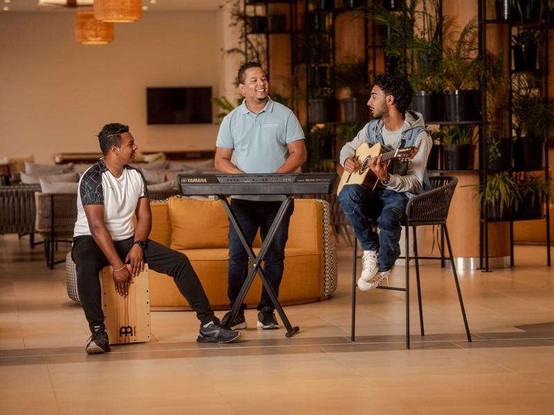 Tři muži hrají hudbu uvnitř v útulném a uvolněném prostředí.