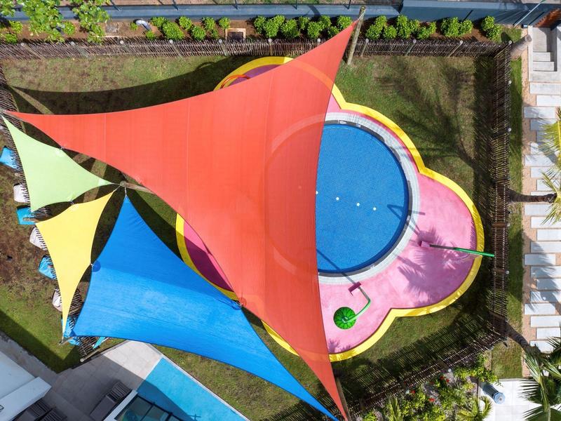 Pestré sluneční plachty nad bazénem ve tvaru květiny v zahradní oblasti