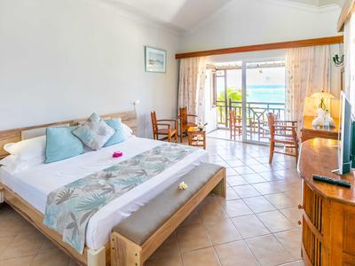 Helles Hotelzimmer mit Doppelbett, Sitzecke und Balkon mit Meerblick.