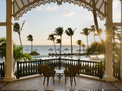 Blick auf Palmen und Meer von einem Balkon mit Stühlen und Tisch in einem Hotel