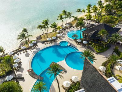 Vista di una piscina tropicale dell'hotel con palme e spiaggia vicina.
