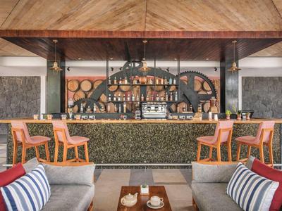 Moderní hotelový bar s dřevěným stropem, oranžovými židlemi a útulnými posezeními.