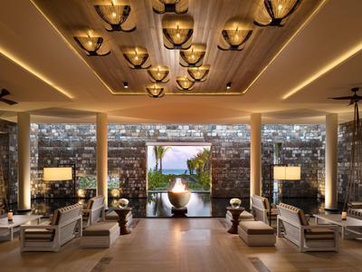 Elegantní hotelová hala s moderním osvětlením a výhledem na bazén a moře.