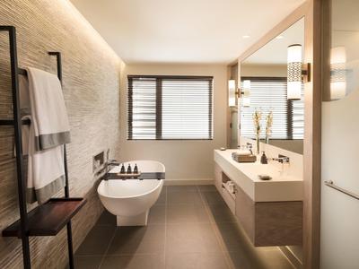 Moderní koupelna s toaletou, umyvadlem, zrcadlem a držákem na ručníky v světlém designu.