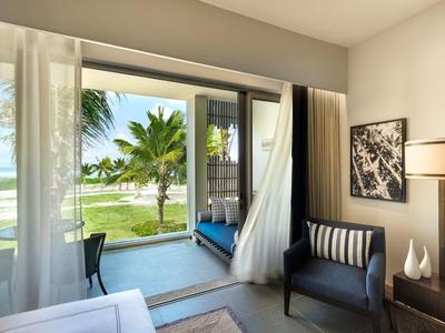 Světý moderní hotelový pokoj s balkonem s výhledem na palmy a pláž.