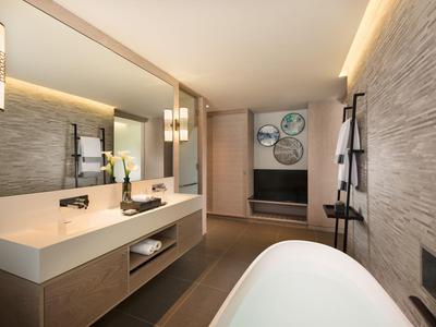 Moderní koupelna s vanou, umyvadlem, velkým zrcadlem a stylovým osvětlením.