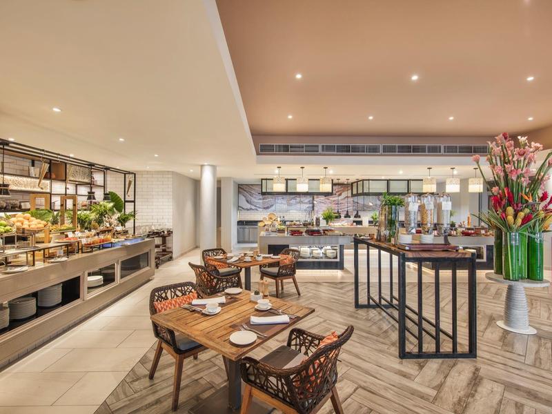 Elegantní hotelová restaurace s bufetovou částí a prostřenými stoly v teplém osvětlení.