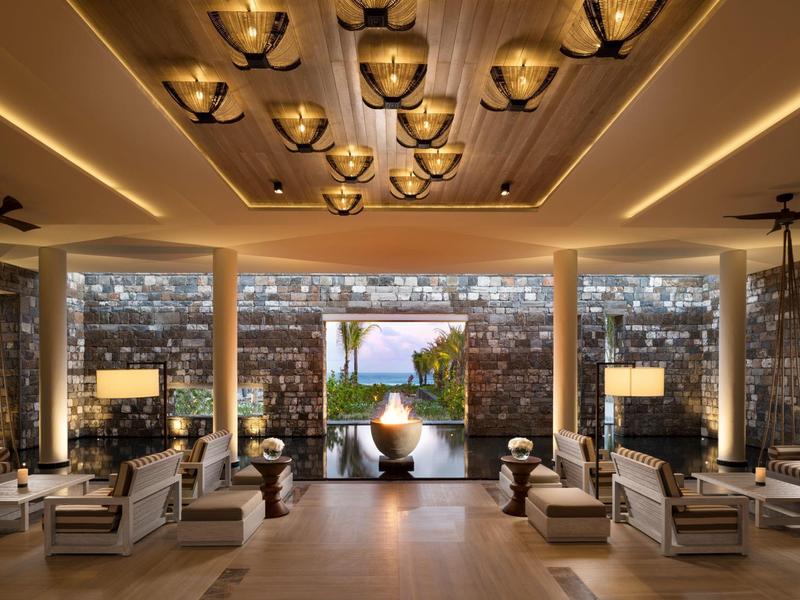 Elegantní hotelová hala s moderním osvětlením a výhledem na bazén a moře.