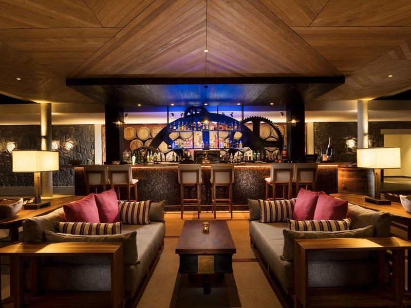 Elegantní hotelový salonek s tmavým dřevem, pohodlnými křesly a teplým osvětlením.