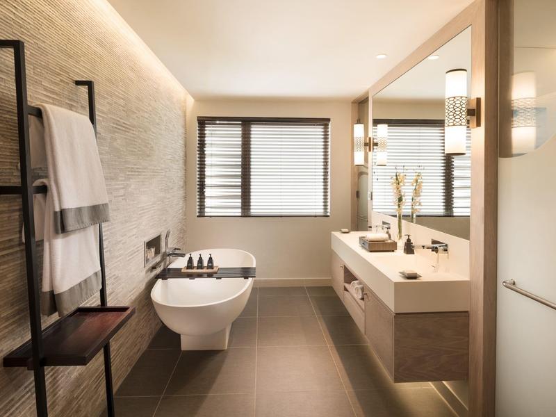 Moderní koupelna s toaletou, umyvadlem, zrcadlem a držákem na ručníky v světlém designu.