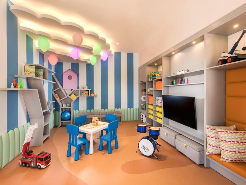 Barevná herna pro děti se stolem, židlemi, hračkami a televizí.