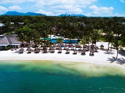 Strandresort met palmbomen, rieten parasols en een kalme zee onder een blauwe lucht.