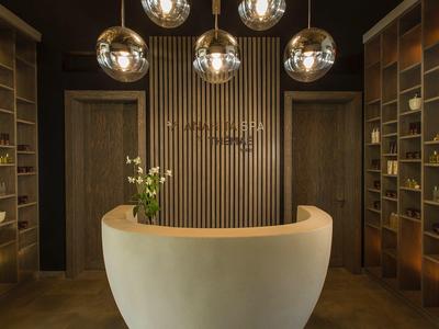 Moderne hotelreceptie met gebogen balie, warme verlichting, houten planken en decoratieve planten.