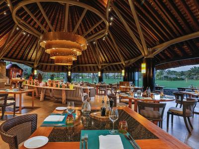 Ruim openluchtrestaurant met houten dak, moderne kroonluchters en gedekte tafels.