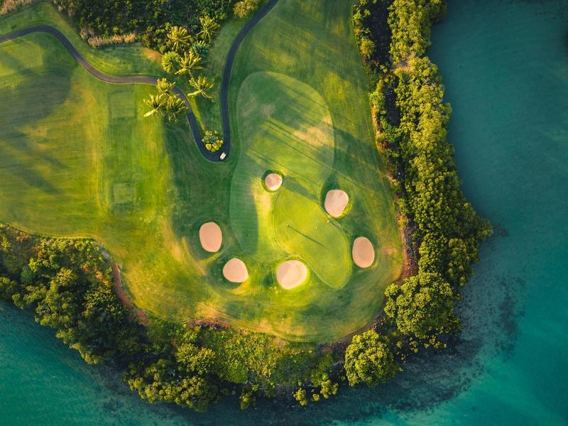 Luchtfoto van een golfbaan omringd door turquoise water en groen.