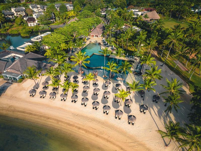 Luchtfoto van een tropisch strandresort met ligbedden en parasols langs de kust.