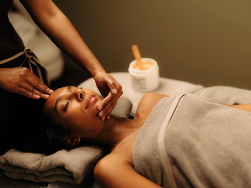 Iemand krijgt een ontspannende gezichtsbehandeling in een spa met gedimd licht.