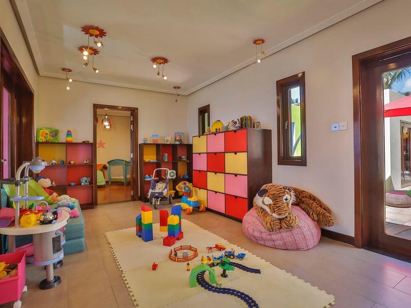 Lichte speelruimte voor kinderen met speelgoed, kleurrijke opbergkasten en grote ramen bij een patio.