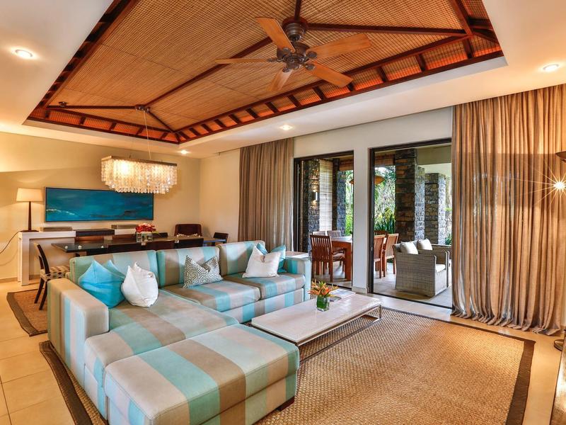 Ruime, stijlvolle hotellounge met grote bank, houten plafond en glazen deuren naar terras.