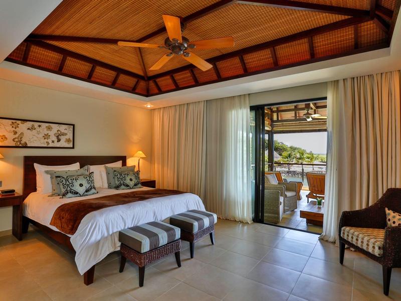 Gezellige hotelkamer met houten plafond, groot bed, lampen en balkon met uitzicht buiten.