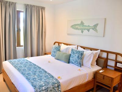 Camera d'hotel moderna con letto grande, dettagli blu e mobili in legno accanto a una finestra.