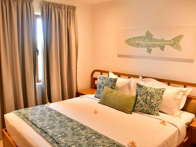 Camera d'hotel accogliente con letto grande, cuscini decorativi e tende alla finestra.