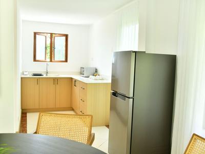 Cucina moderna con armadietti chiari, grande frigorifero e piccola finestra che lascia entrare la luce.