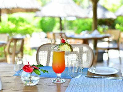 Un cocktail colorato con guarnizione su un tavolo apparecchiato all'aperto in un giardino d'hotel.