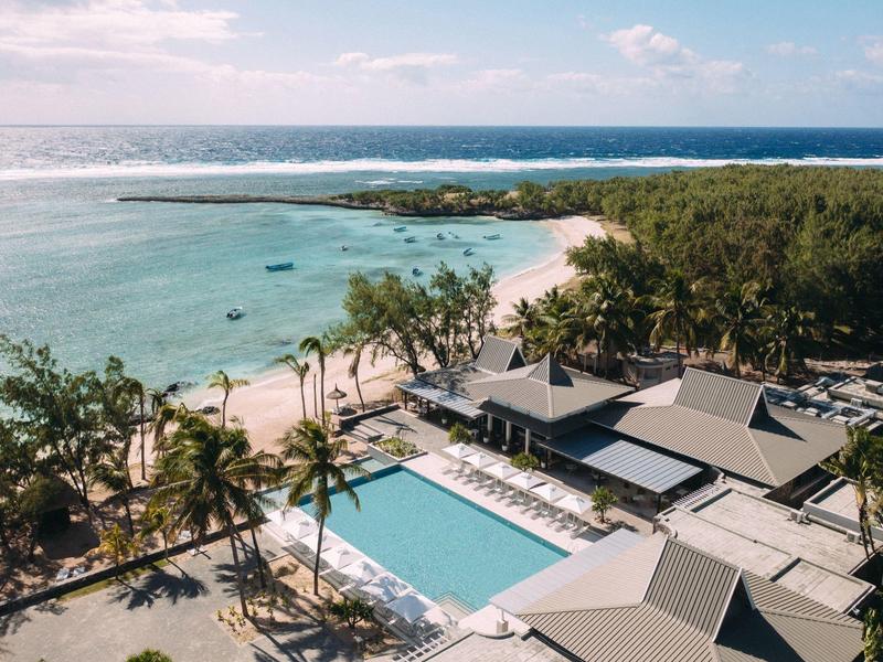 Vue sur un resort tropical avec piscine, palmiers et plage au bord de l'océan