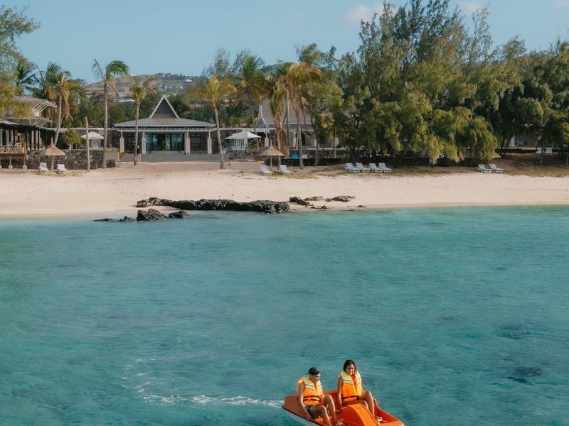 Eau turquoise claire près d'une plage avec deux personnes sur un pédalo.