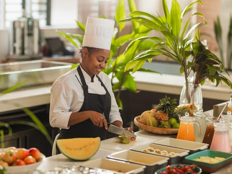 Cuisinière dans la cuisine de l'hôtel prépare des fruits frais pour les clients.
