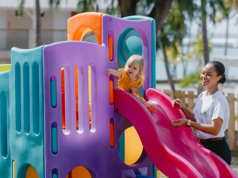 Des enfants jouent sur une structure de jeu colorée avec un toboggan en plein air.