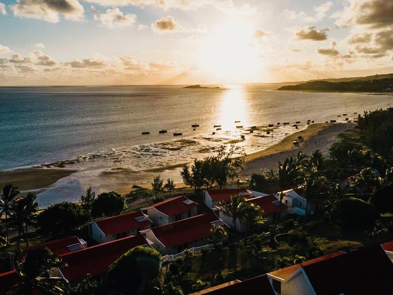 Strand bij zonsondergang met hotelgebouwen en palmbomen ervoor