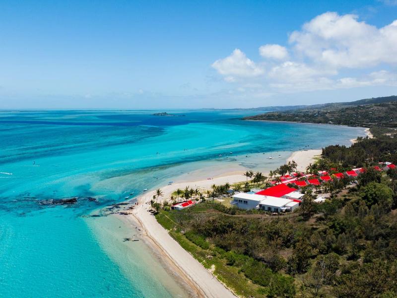 Kustlandschap met turquoise zee en strandhotel onder een blauwe lucht.