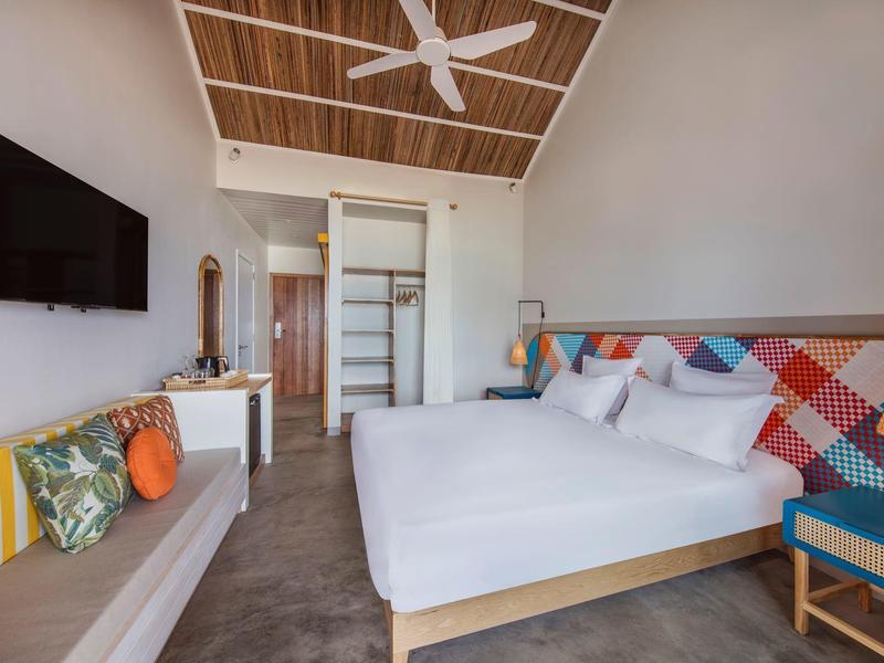 Moderne hotelkamer met groot bed, plafondventilator en flatscreen-tv.