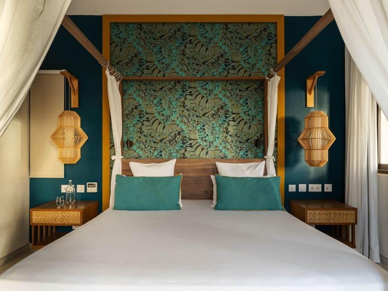 Ložnice s manželskou postelí, modrými stěnami a dekorativními závěsy.