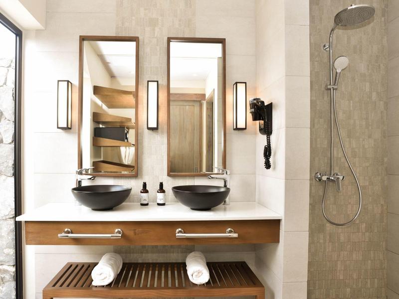 Moderní hotelová koupelna s dvojnásobnou umyvadlovou skříňkou, zrcadly a sprchou.