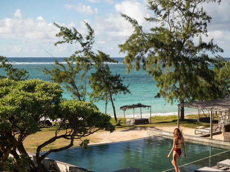 Výhled na moře s bazénem, stromy a osoba za slunečného dne