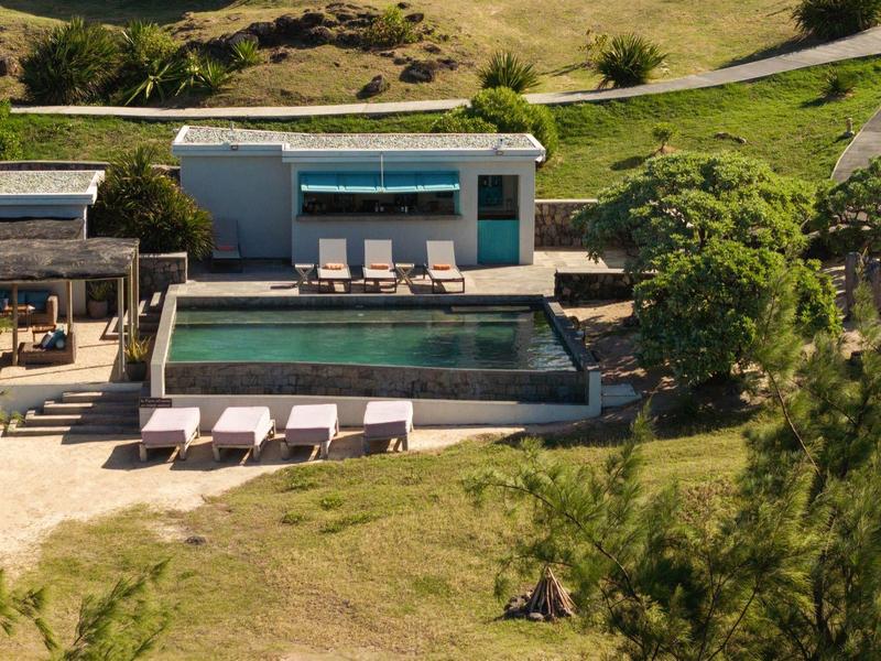 Moderní bazén s lehátky a pavilonem na venkově vedle hotelu.