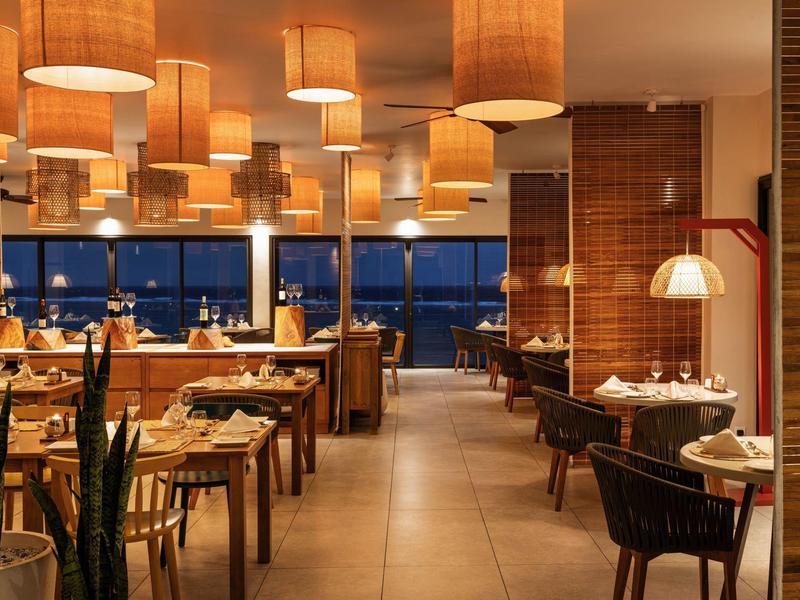 Moderní restaurace s teplým osvětlením a elegantně prostřenými stoly v noci.